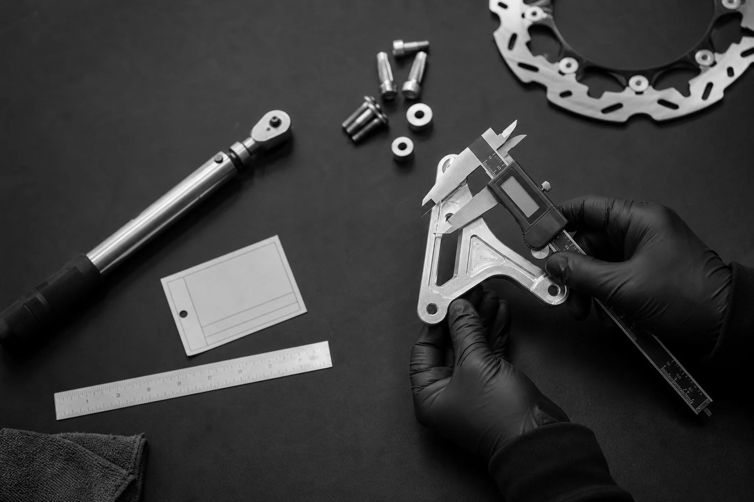 Technician measuring an unbranded machined brake bracket for fitment verification